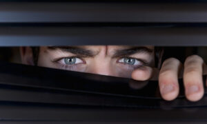 Young looking behind a blind, frowning